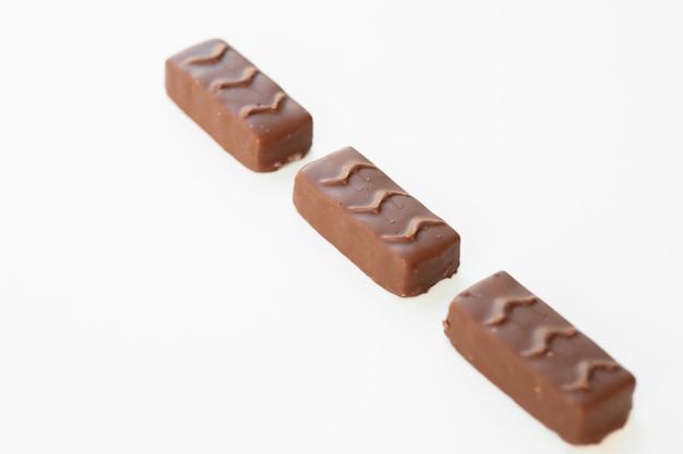 白い背景に分離されたヌガーカラメルとナッツとチョコレート菓子の山