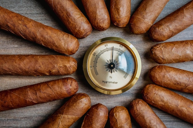 Photo pile of cigars with humidor hygrometer on the wooden background