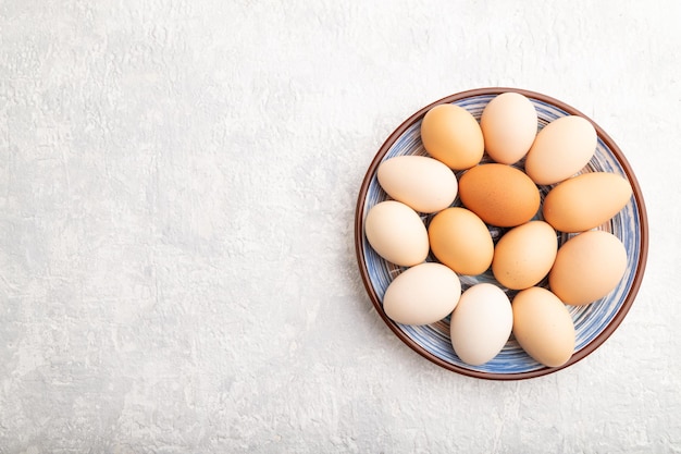 Pile of colored eggs on plate on a gray concrete background top view copy space