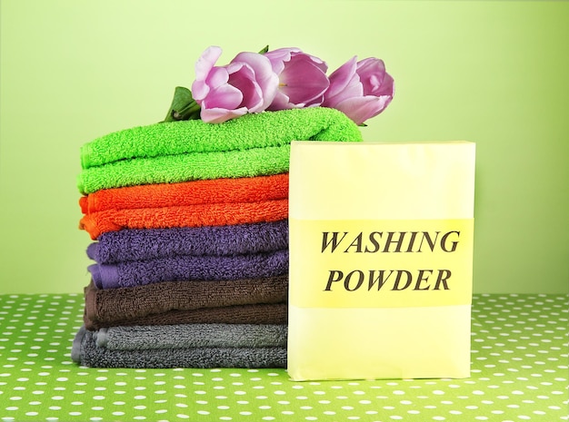 Photo pile of colorful towels wash powder on green background