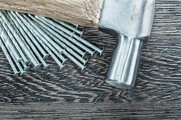 Pile of construction nails claw hammer on wooden board