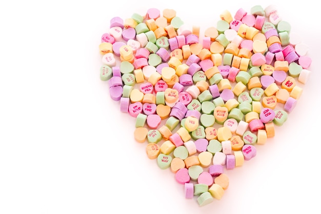 Pile of conversation heart candies in heart shape.