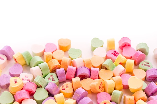 Pile of conversation heart candies on white background.