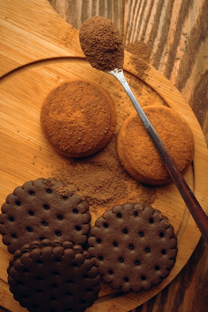 A pile of cookies and a spoonful of cocoa.