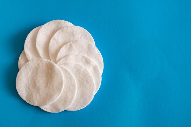 Pile of cotton disks on a blue table closeup