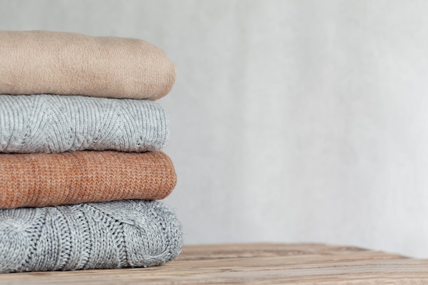 Pile of cozy knitted sweaters on a neutral background Warm concept