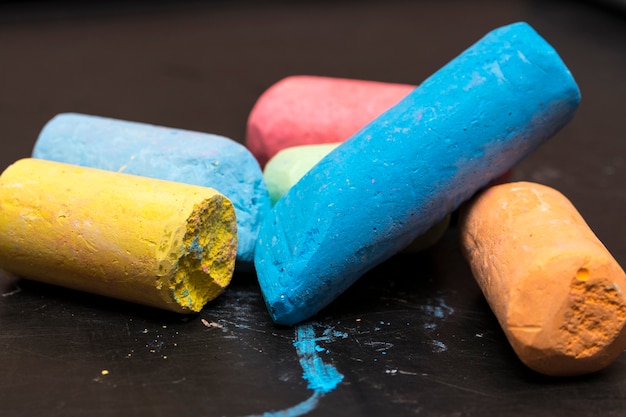 Pile of crayons of different colors on a black background blackboard