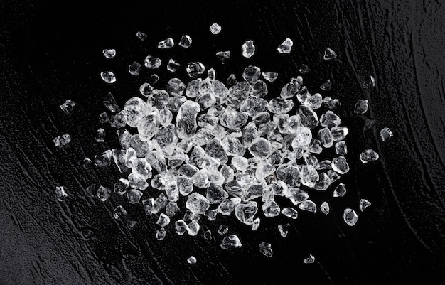 Pile of crushed ice cubes on black stone background, top view with copy space