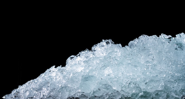 Pile of crushed ice cubes on dark background with copy space. Crushed ice cubes foreground for beverages.