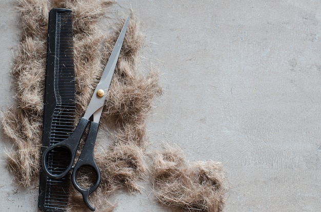 Pile of cut hair, scissors for haircuts and comb. Tools for haircuts.