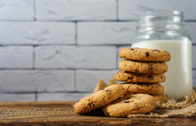 A pile of delicious chocolate chip cookies on a napkin with a bottle of milk on the kitchen table a copy of the space