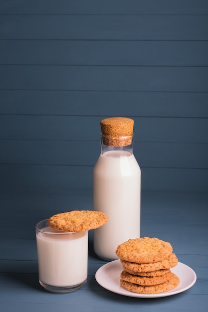 A pile of delicious homemade cookies on a white plate, a bottle of milk and a glass of milk