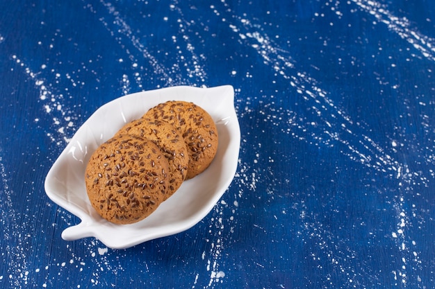 Photo pile of delicious oatmeal biscuits with seeds on white plate.