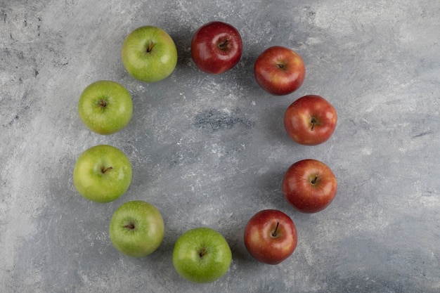 Куча вкусных красных и зеленых яблок на мраморной поверхности.