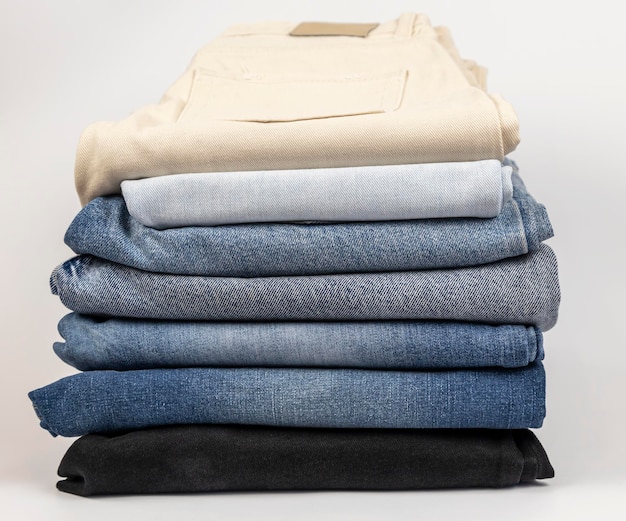 A pile of different jeans on a white background The concept of updating the wardrobe