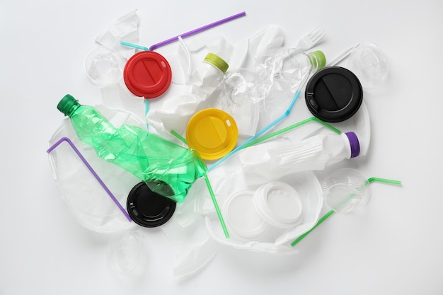 Pila di diversi oggetti in plastica su sfondo bianco piatto