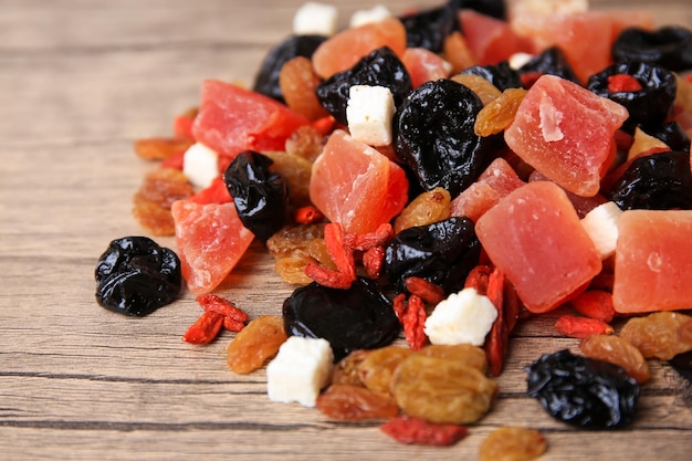 Pile of different tasty dried fruits on wooden table closeup