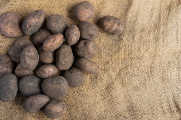 Foto mucchio di patate sporche sul lato sinistro di una stuoia di iuta