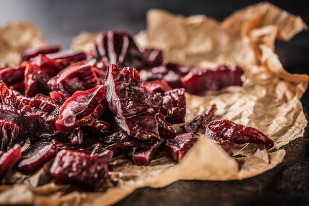 A pile of dried beef jerky pieces on paper and cutting board.