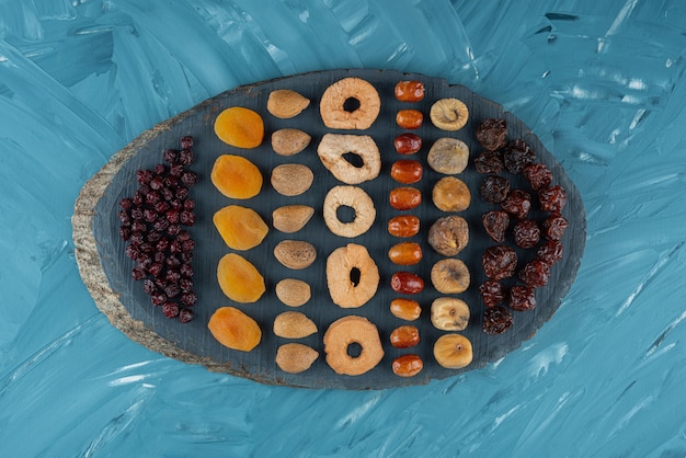 Pile of dried tropical fruits placed on a wooden board .