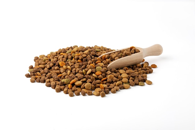 A pile of dry cat and dog food and a scoop for food on a white background.