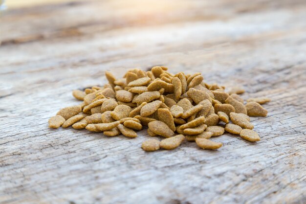 Pile of dry cat food on wooden background. 