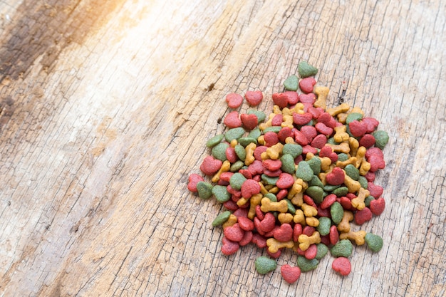 Pile of dry dog food on wooden background. 