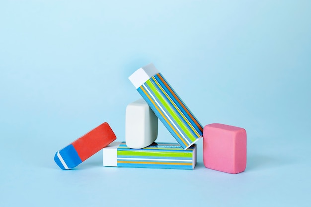 Pile of erasers on light blue background School study concept