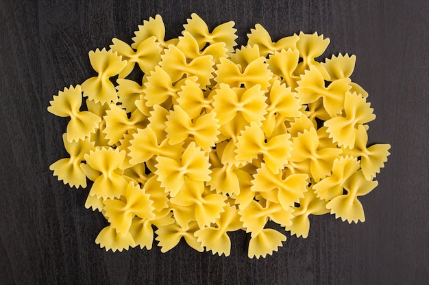 A pile of farfalle pasta on black background