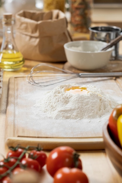 Pile of flour with broken raw egg on wooden board