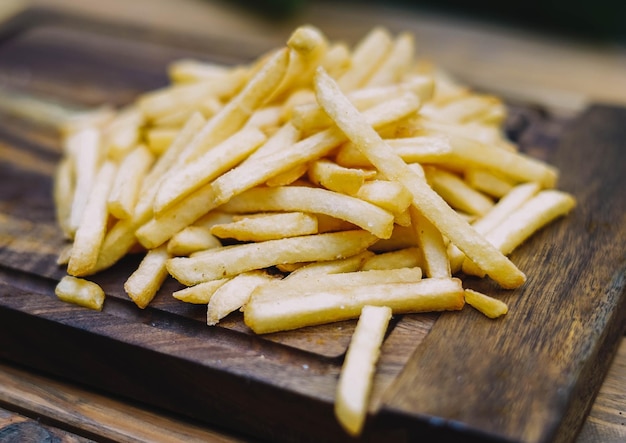 A pile of french fries on a wooden cutting board