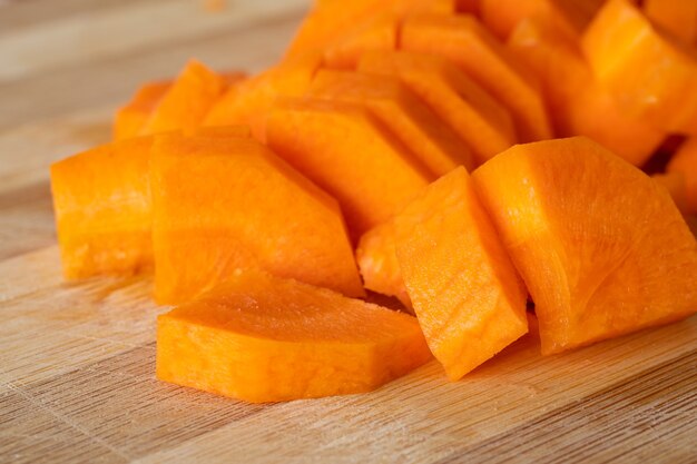 A pile of fresh carrots cut on wooded board