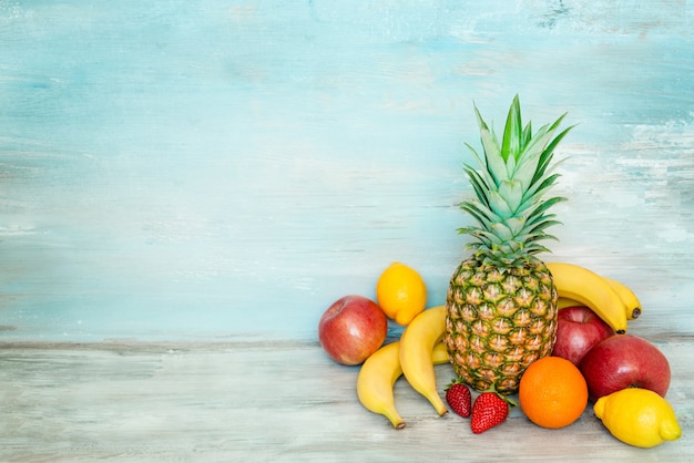 A pile of fresh fruits in front of a blue rustic wood.