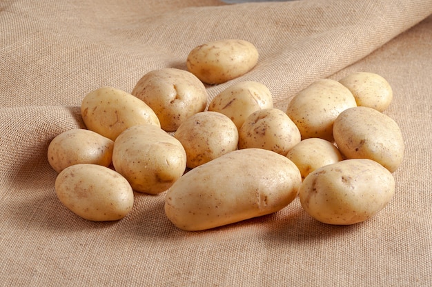 Pile of fresh raw potatoes on a beige textile surface