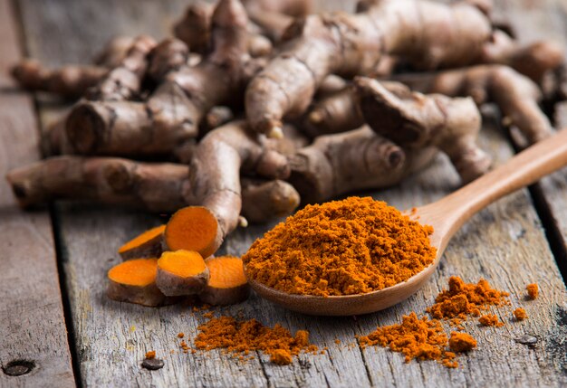 Pile of fresh turmeric roots on wooden table