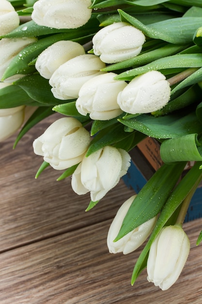 Pile  of fresh white  tulips on wooden table