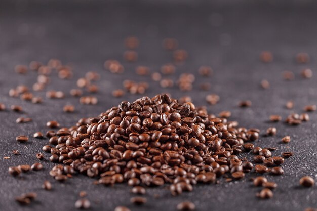 A pile of freshly roasted coffee beans on a dark background