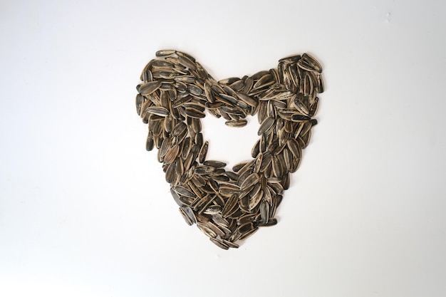 Pile of fried sunflower seeds with heart or love shape isolated on white background