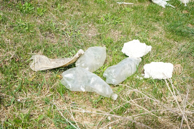 녹색 잔디의 배경에 쓰레기 더미 플라스틱 병 생태의 개념