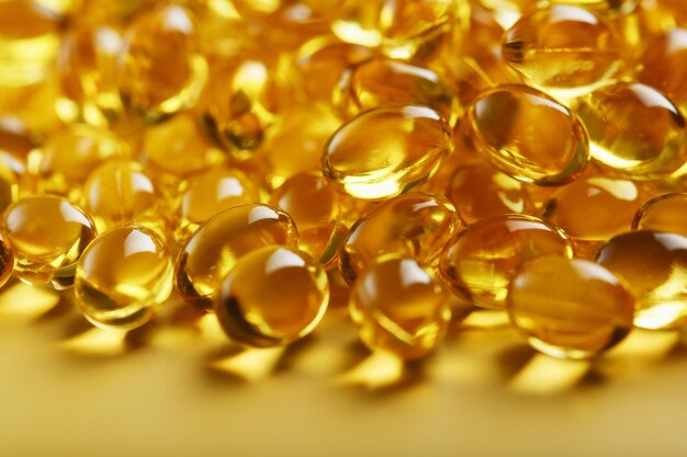 Pile of golden capsules of vitamin D3 on a yellow background with free space Biologically active substances of the calciferol group are fatsoluble organic compounds