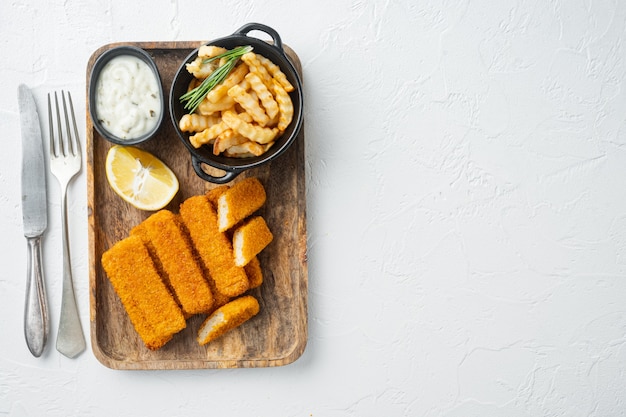 Pila di bastoncini di pesce fritti dorati con salsa di aglio bianco su vassoio in legno