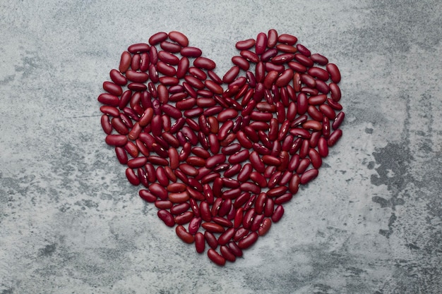 A pile grains red kidney beans heart shape on concrete background