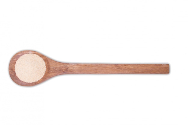 A pile of granulated garlic powder on wooden spoon isolated on white 