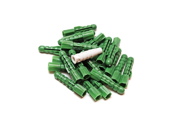 A pile of green plastic screws with one that has a white cap.