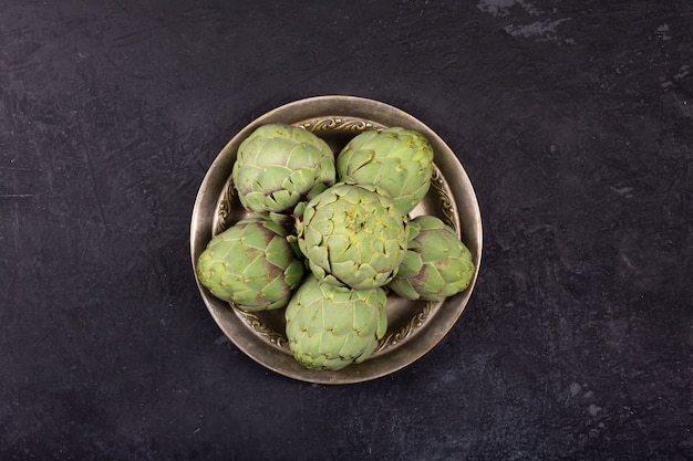 Pile of green Spanish or Italian Artichokes on the metal rustic plate