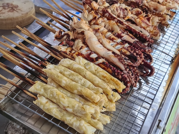 市場の屋台で販売されている焼きイカの串焼きの山