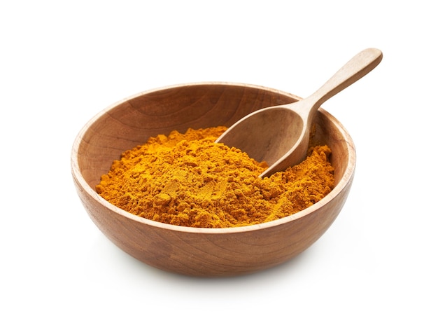 a pile of ground turmeric powder or curcumin powder in wood plate and scoop isolated background