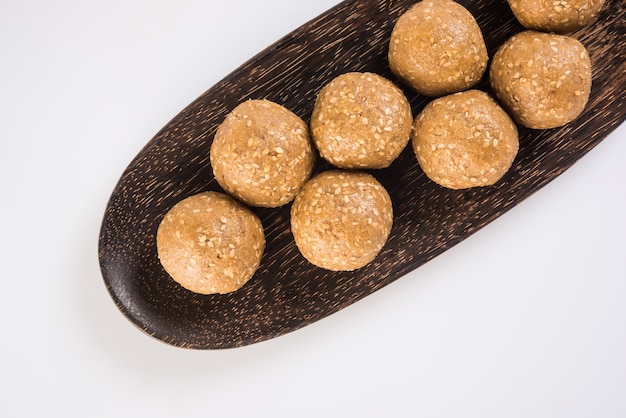 Pile of handmade Tilgul Laddu or Til Gul Laddoo made up of jaggery or gud and sesame seeds for Makar Sankranti festival, served in a bowl.  selected focus