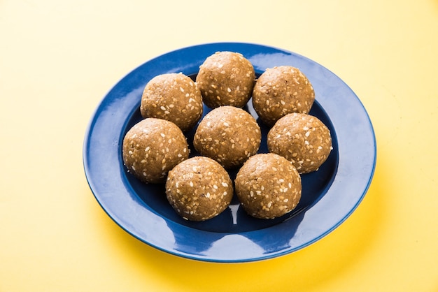 Makar Sankranti 축제를 위해 재 거리 또는 gud와 참깨로 만든 수제 Tilgul Laddu 또는 Til Gul Laddoo 더미가 그릇에 담겨 제공됩니다. 선택한 초점