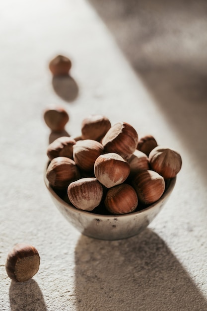Pile of hazelnuts filbert in a bowl on a white background. Fresh nuts in their shells.